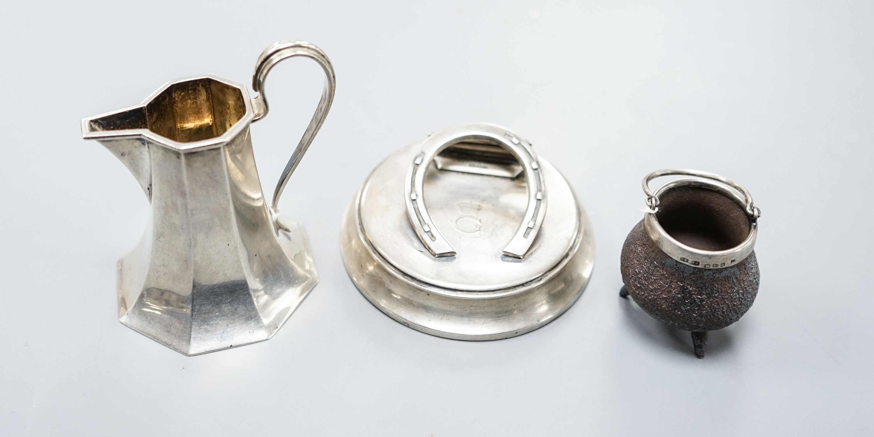 An Edwardian silver horseshoe letter clip, London, 1907, 86mm, a silver cream jug and a silver mounted Doulton Lambeth stoneware miniature cauldron.